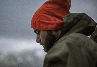 Close-up of man in red beanie looking down in winter