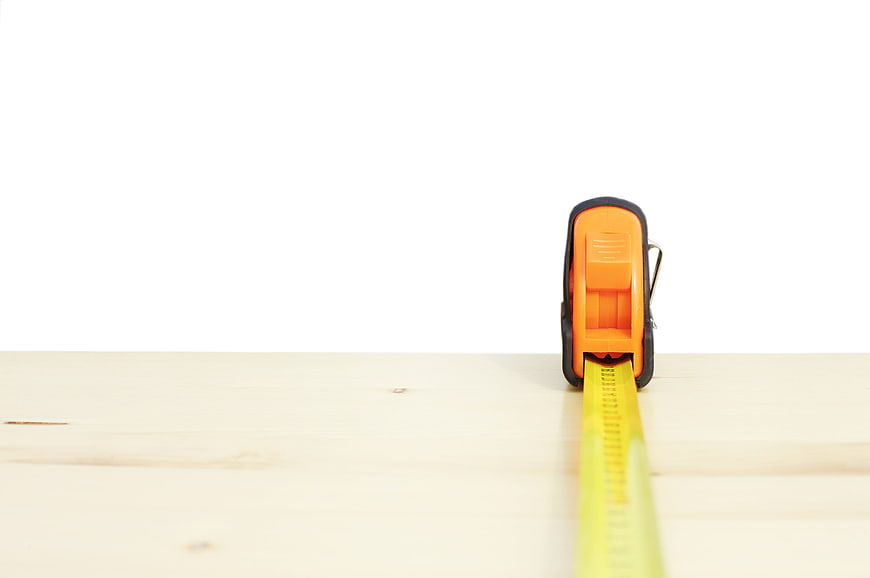 Orange Tape Measure on Wooden Surface with White Background