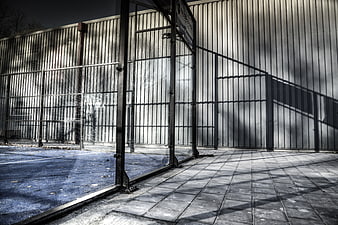 Urban Tennis Court Entrance with Metal Fence and Shadows