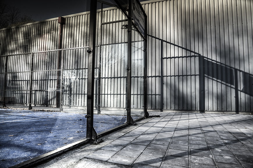 Urban Tennis Court Entrance with Metal Fence and Shadows
