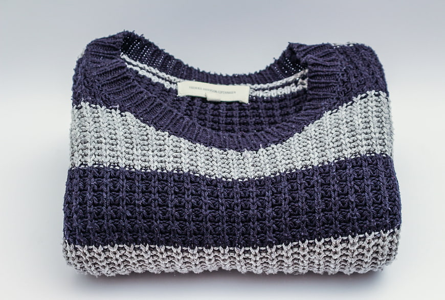 Folded Navy and Grey Knit Sweater on White Background