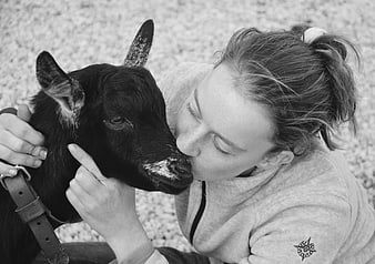 Young woman kissing a black goat in black and white