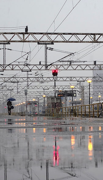 Woman with Umbrella Walking on Rainy Train Station Platform