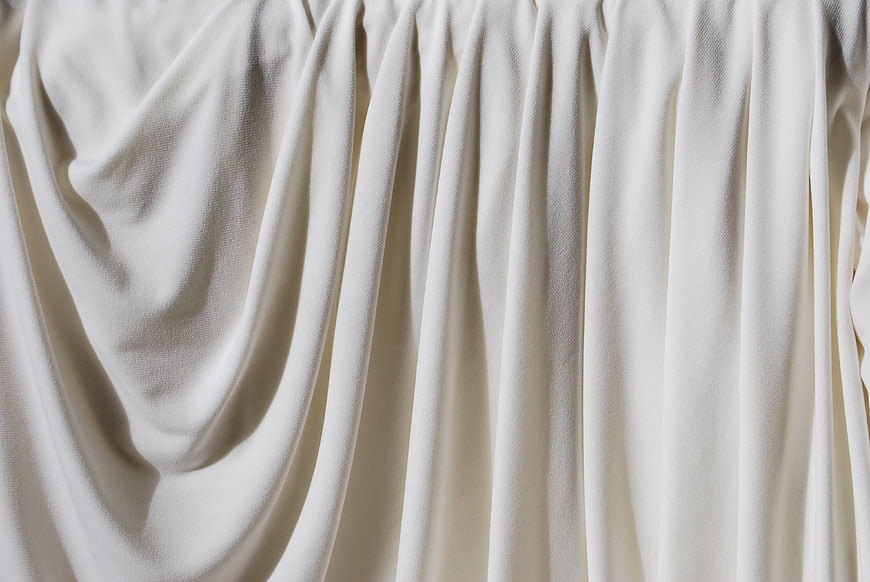 Close-up of draped cream fabric with soft folds and texture