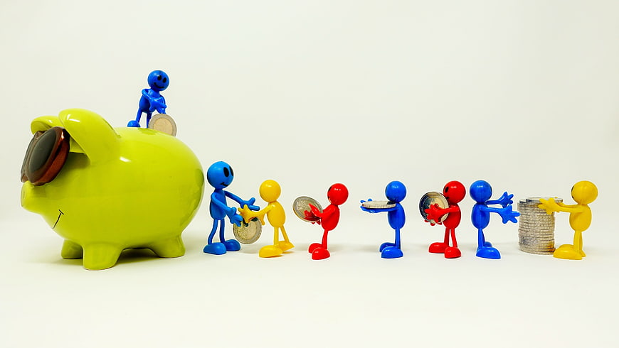 Colorful figurines saving coins in a green piggy bank