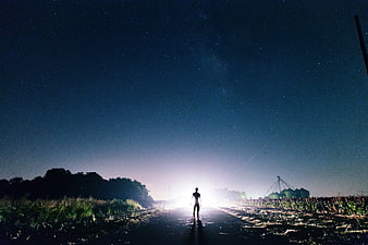 Silhouette of Man Walking on Rural Road Under Starry Night Sky