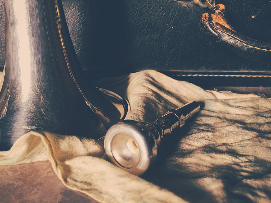 Close-up of silver trumpet mouthpiece on beige cloth