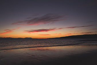 Serene Sunset Over Ocean Beach with Pink Clouds