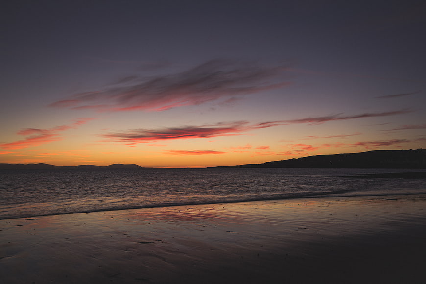 Serene Sunset Over Ocean Beach with Pink Clouds
