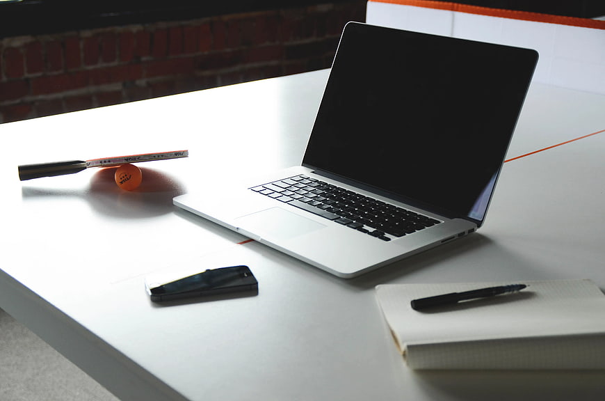 Modern Workspace with Laptop, Smartphone, and Notebook on White Desk
