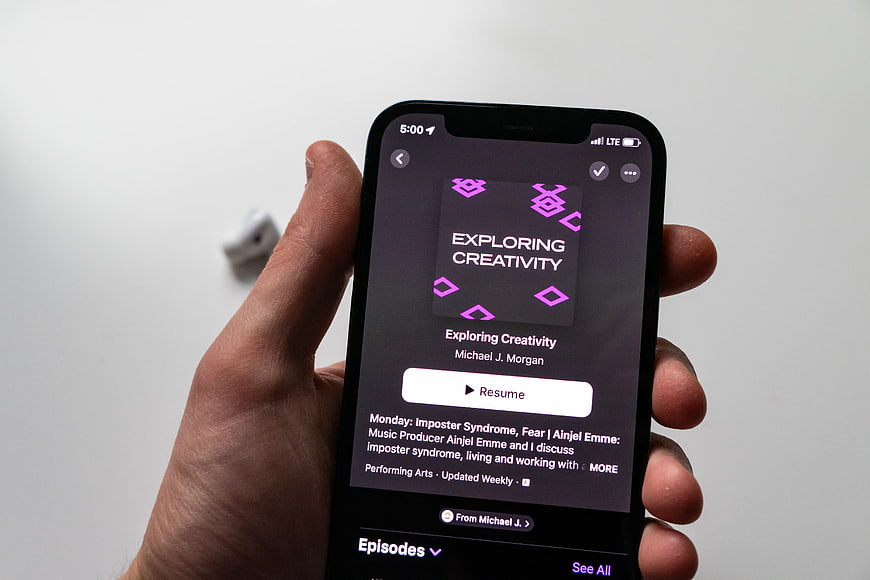 Hand Holding Smartphone Displaying Podcast App Interface