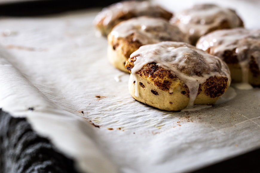 Freshly Baked Glazed Cinnamon Rolls on Parchment Paper