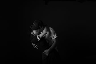 Black and white studio portrait of a couple kissing in the dark