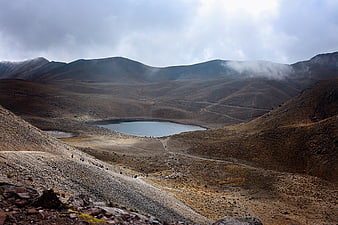 Highland Mountain Lake Landscape With Hikers And Dramatic Clouds