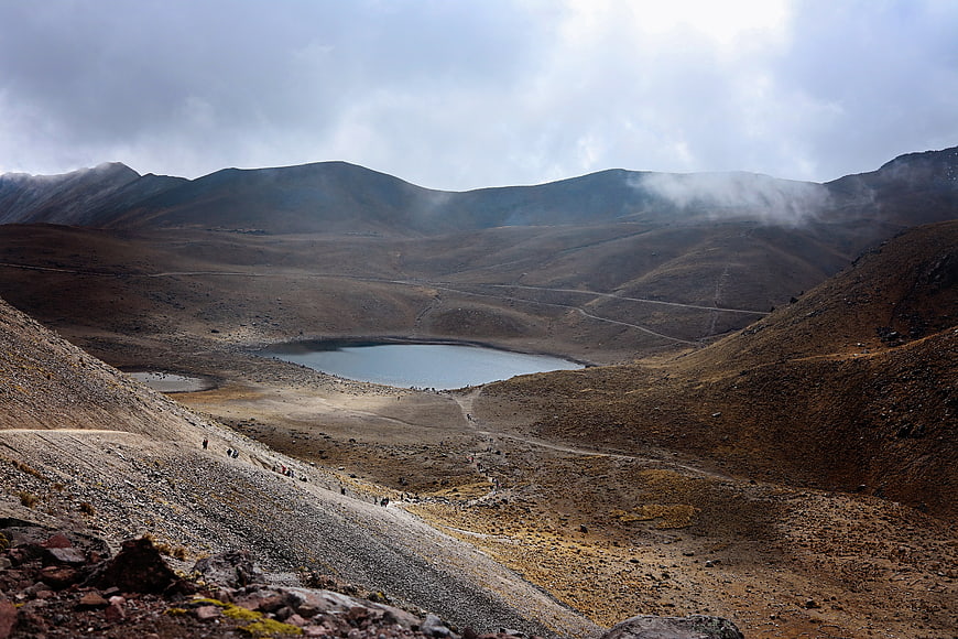 Highland Mountain Lake Landscape With Hikers And Dramatic Clouds