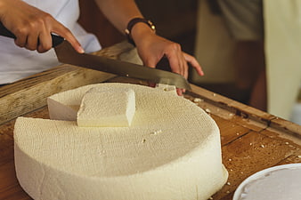 Artisan Cutting Fresh Alpine Cheese Wheel On Wooden Table