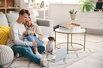 Young couple relaxing at home with dog and pizza