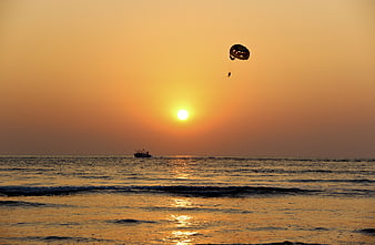 Parasailing Silhouette Against Golden Sunset Ocean Horizon