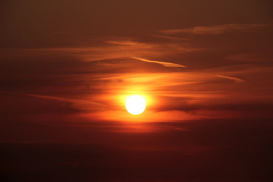 Vibrant orange sunset with bright sun and clouds