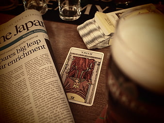 Justice Tarot Card on Wooden Table with Newspaper and Glass