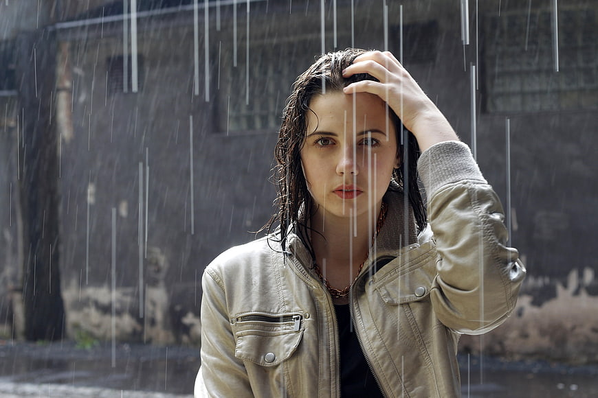 Portrait of a young woman standing in heavy rain