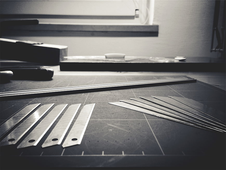Black and white razor blades on a cutting mat in a workshop