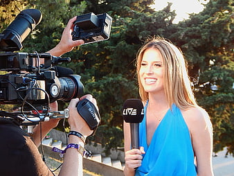 Female reporter with microphone being filmed outdoors