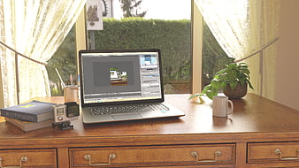 Home office workspace with laptop, camera, and books by window
