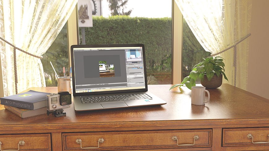Home office workspace with laptop, camera, and books by window