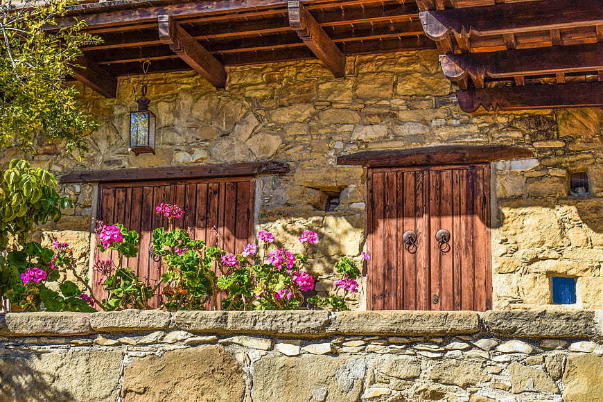 Traditional Stone House with Wooden Shutters and Pink Flowers