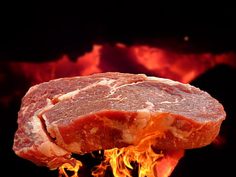 Raw Beef Steak Floating Above Open Flames on Black Background