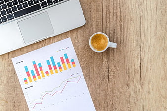 Laptop, Coffee, and Business Charts on Wooden Desk