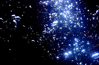 Abstract blue bubbles rising in dark liquid