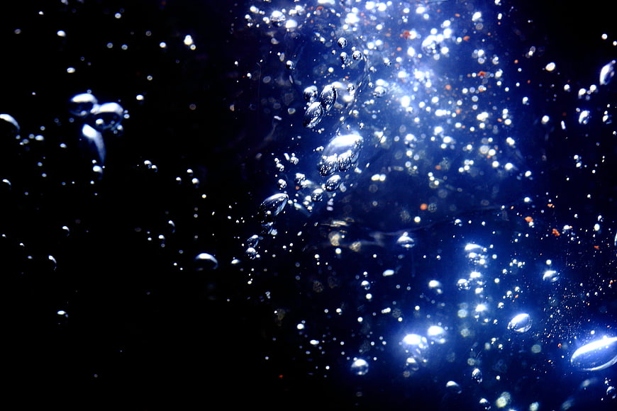 Abstract blue bubbles rising in dark liquid