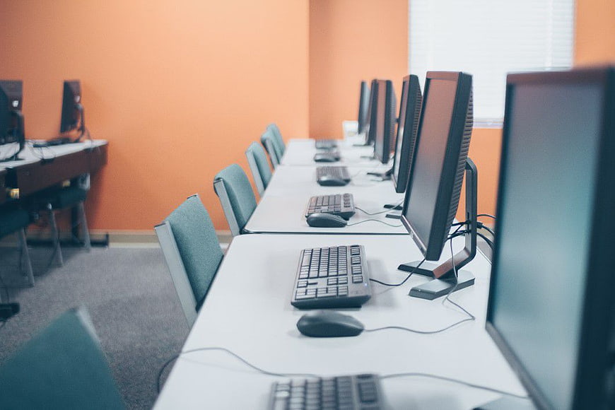 Empty Computer Lab with Orange Walls and White Desks