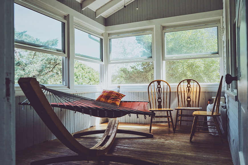 Cozy Sunlit Porch with Hammock and Wooden Chairs