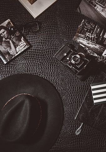 Vintage Camera, Hat, and Photos on Textured Leather Background