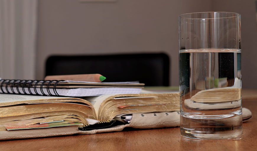 Glass of water next to open book and study notes