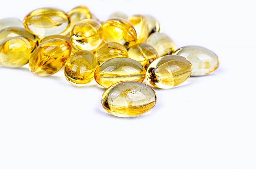 Yellow fish oil capsules on white background