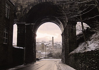 Snowy Road Under Stone Archway in Winter Town