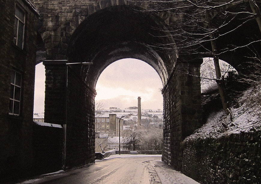 Snowy Road Under Stone Archway in Winter Town