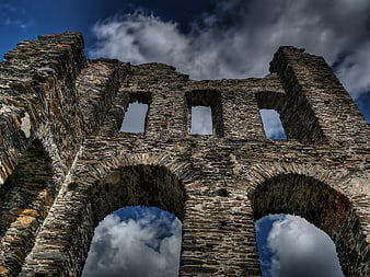 Low angle view of ancient stone castle ruins against dramatic sky