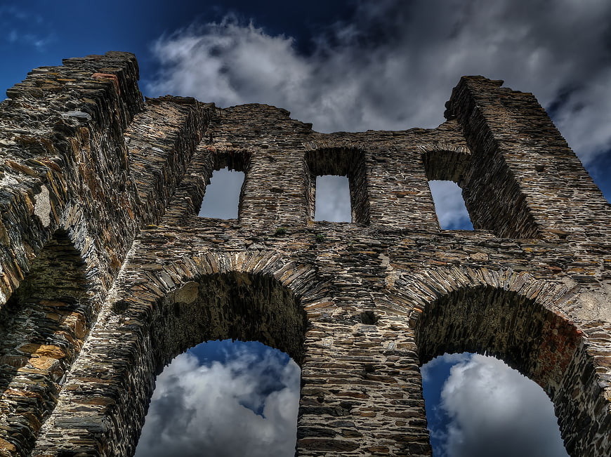 Low angle view of ancient stone castle ruins against dramatic sky