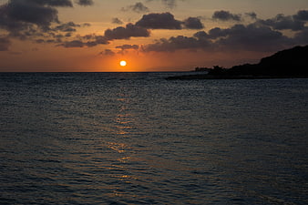 Serene Sunset Over Ocean with Silhouette Coastline
