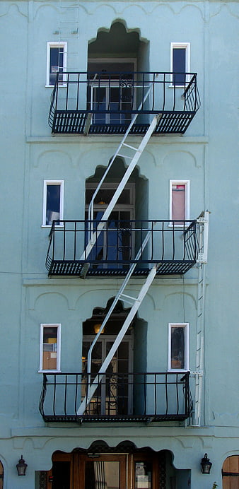 Vertical view of light blue building facade with fire escape