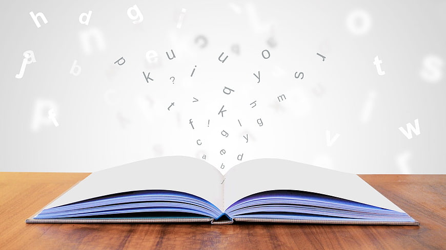 Open book with floating alphabet letters on wooden table
