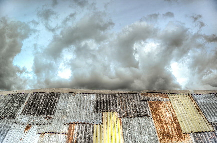 Rusty corrugated iron roof under dramatic cloudy sky