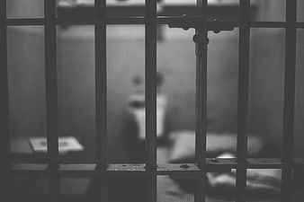Black and white view through prison bars into a cell