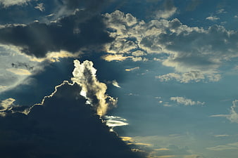 Dramatic Sun Rays Breaking Through Dark Clouds in Blue Sky