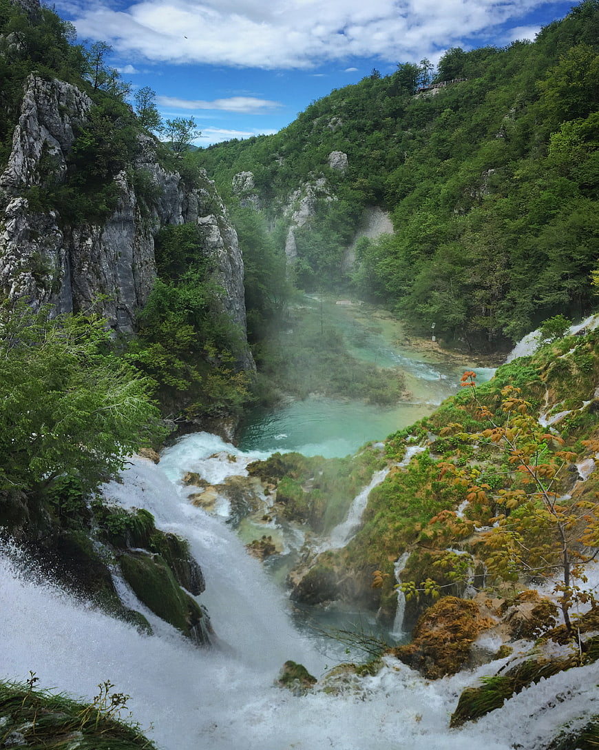 Scenic waterfall cascading into turquoise pool in lush green canyon